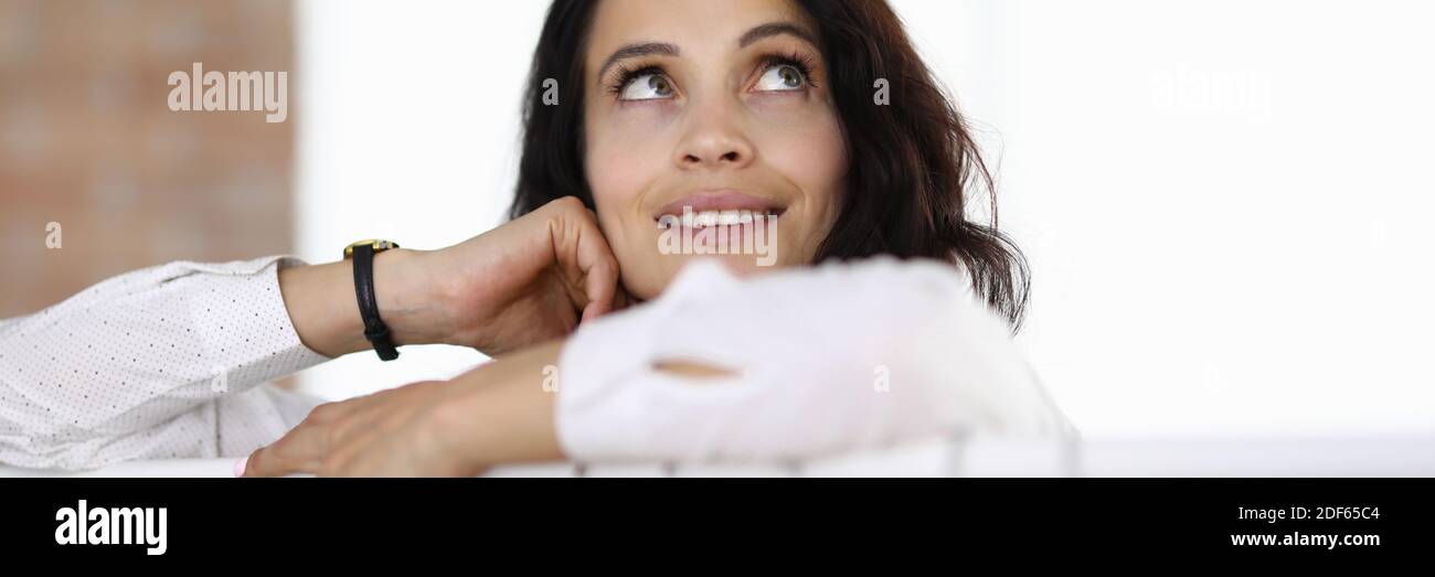 Woman stands with her elbows on hanger and looks up dreamily Stock ...