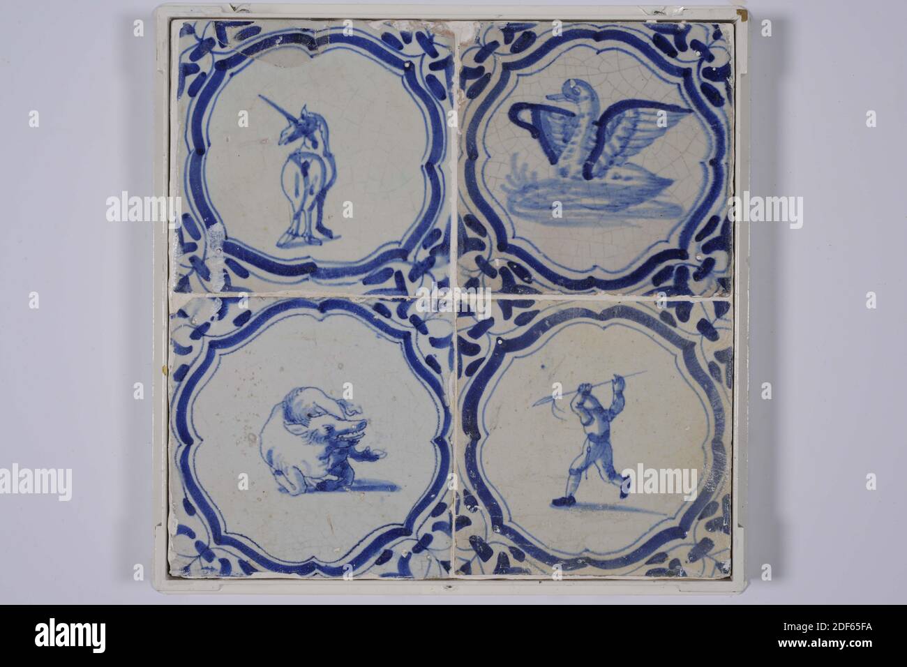 tile field, Anonymous, first half 17th century, With frame: 28.8 x 28.8 x 3.4cm (288 x 288 x 34mm), General: 12.8 x 12.8 x 1.3cm (128 x 128 x 13mm), unicorn, pig , duck, hunter, northern netherlands, Tile field of four tiles (two by two) made of earthenware covered with tin glaze painted in blue. The tile field depicts animals in braces and a hunter with a spear. Clockwise: a unicorn, a duck, a boar, and the hunter with spear. The tiles have a wing leaf as a corner motif, 1985 Stock Photo