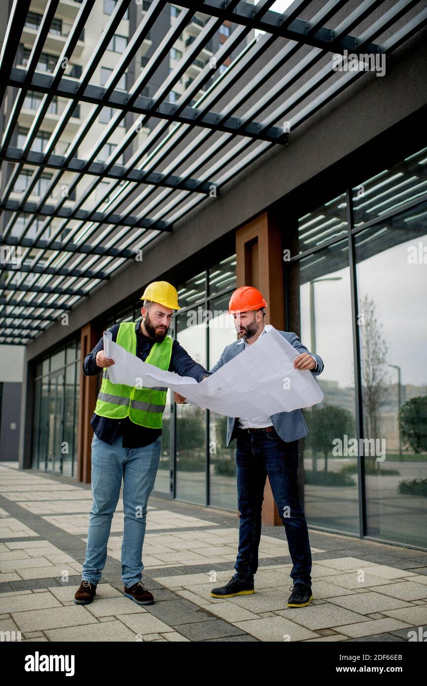 Two architects examining a blueprint and working on a building project. Stock Photo