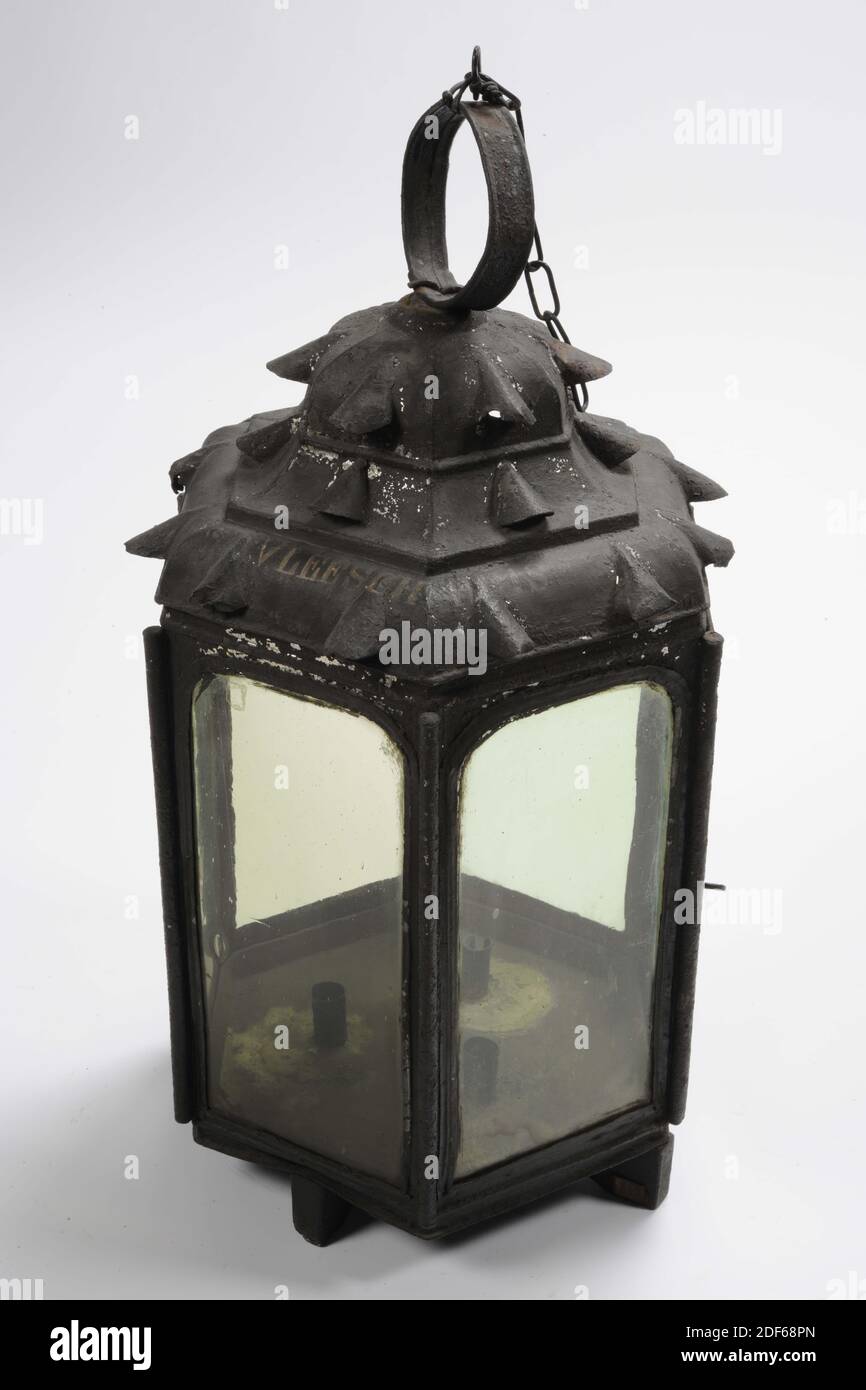 lantern, Anonymous, 18th century, wood, iron, forged, Hexagonal candle lantern made of black painted sheet iron with straight walls. The six walls, reinforced with rods at the corners, have arched windows, one of which is a hinged door. One of the windows is missing. The bottom is mounted on a wooden supporting cross and on the inside there are three cylindrical candle holders. The pagoda-shaped roof, which is profiled in three layers, has arch-shaped, round-covered ventilation holes. The bottom layer two holes per side and the two above one. On top of the lantern roof is a flat sheet iron Stock Photo