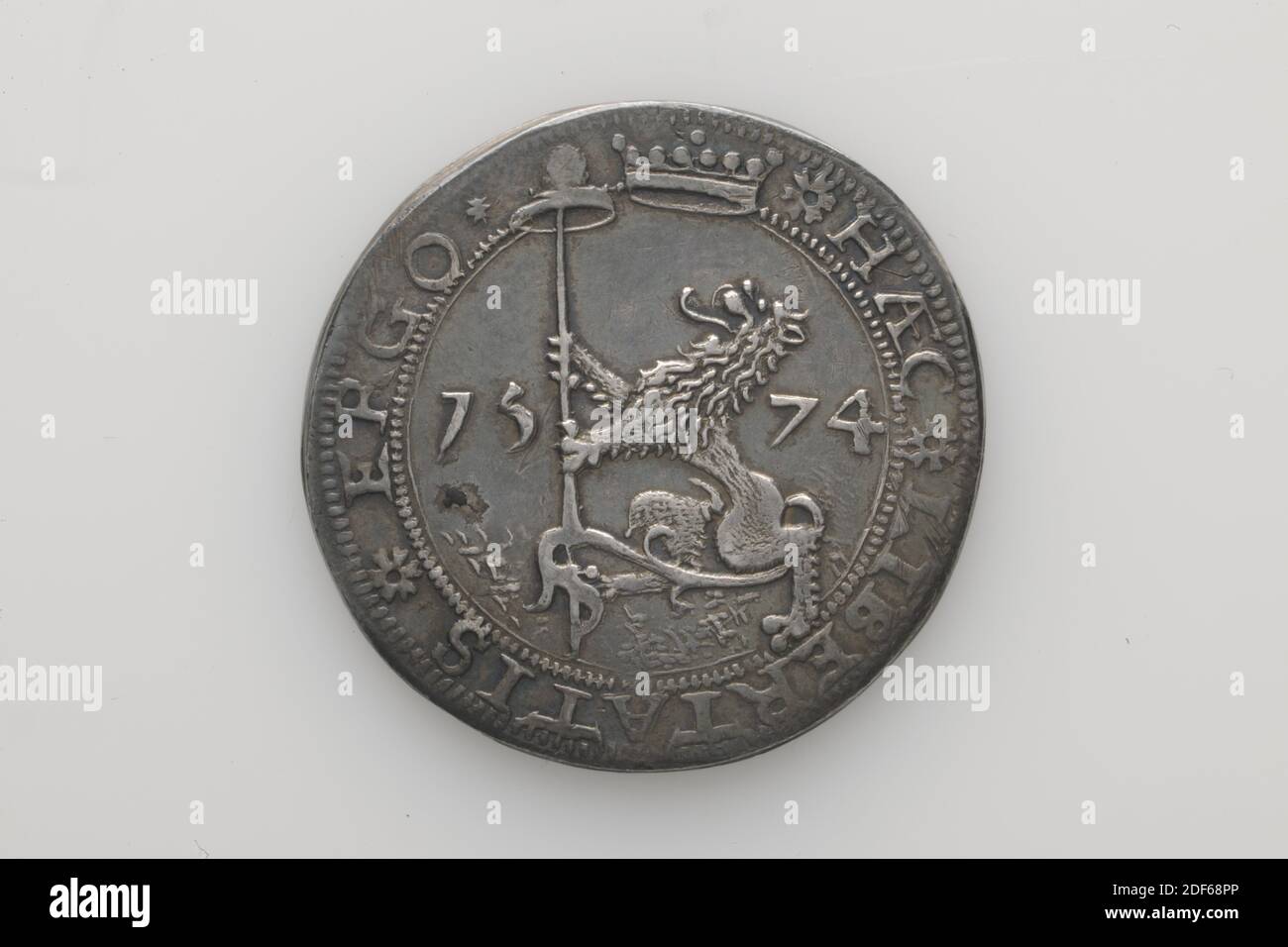 Anonymous, Verm. First quarter of the 17th century, minted, General: 3.7 x 0.2cm (37 x 2mm), Weight: 18.7g, Silver key of 20 cents paper emergency coin. The paper emergency coin was minted during the siege of Leiden, 1574. On the obverse is a standing lion, facing left on a ground with a lance with a freedom hat in the claws, between the year 1574. Above the lion, protruding in the rim , a crown is depicted. The circular HAEC LIBERTATIS ERGO runs around this. On the reverse is the central coat of arms of Leiden, depicted as two crossed keys in an ornamented shield, around which are the letters Stock Photo