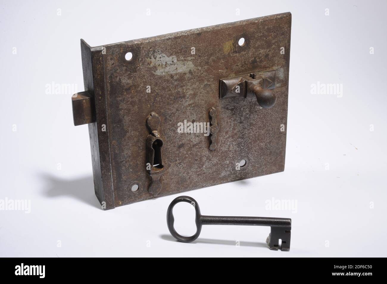 Anonymous, 16th century, Lock: 22.7 x 29.7 x 5.4cm (227 x 297 x 54mm), Key: 7 x 15.2 x 1.2cm (70 x 152 x 12mm), Iron lock with key attributed to the house of PA Van der Werf. The lock consists of an iron plate with a keyhole and a slide with a button. The plate has a perpendicular part with a square opening for the bolt. The keyhole has a leaf-shaped decoration on the top and bottom. The actual lock with tumbler mechanism is riveted to this plate. A simple baluster-shaped decoration has been placed on the place of the rivets. There are four holes in the plate for attachment to the door. The Stock Photo