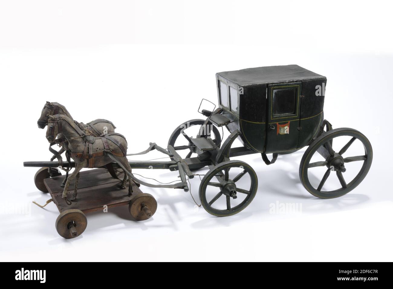 Anonymous, first half of the 19th century, glass, wood, rope, leather, painted, Toy carriage with two horses, a pair of horses, of painted wood. The black and green painted carriage contains two four-wheel axles, with the rear wheels being larger than the front wheels. The coach has a covered hood for the passengers and a separate seat for the coachman. Both doors of the carriage have C.D.F .. under the glass windows. The carriage has two horses, covered with leather and standing on a plateau with four small wheels. The horses' reins are made of rope. The horses' tails are broken off, General Stock Photo
