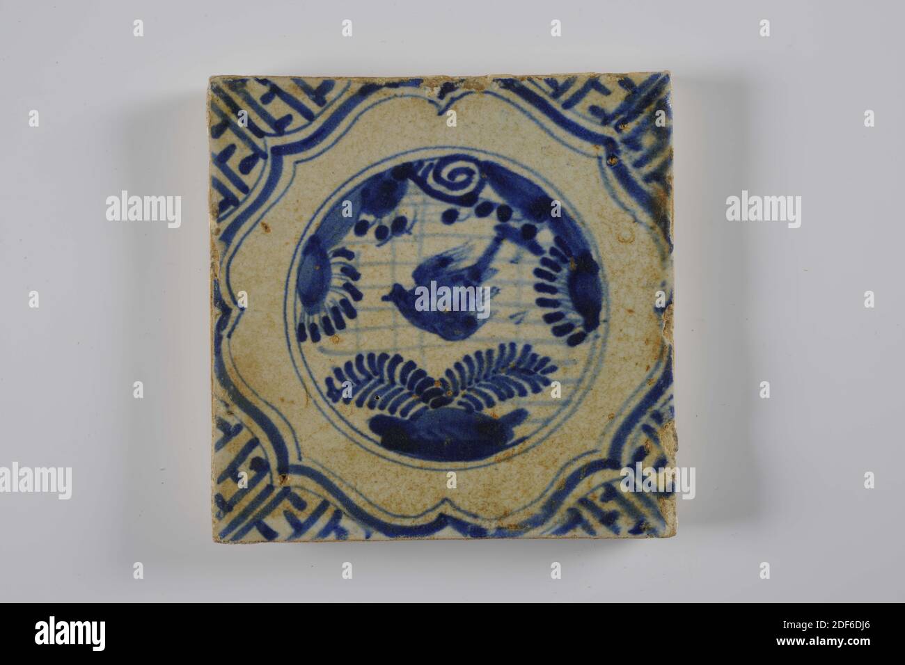 wall tile, Anonymous, second quarter 17th century, tin glaze, earthenware, General: 13.4 x 13.4 x 1.6cm (134 x 134 x 16mm), flower, bird, Earthenware wall tile covered with tin glaze and painted in blue. The tile depicts a Chinese garden within a circle. The image consists of flowers and a bird. The tile has a frame of braces and meanders as corner motif, 1995 Stock Photo