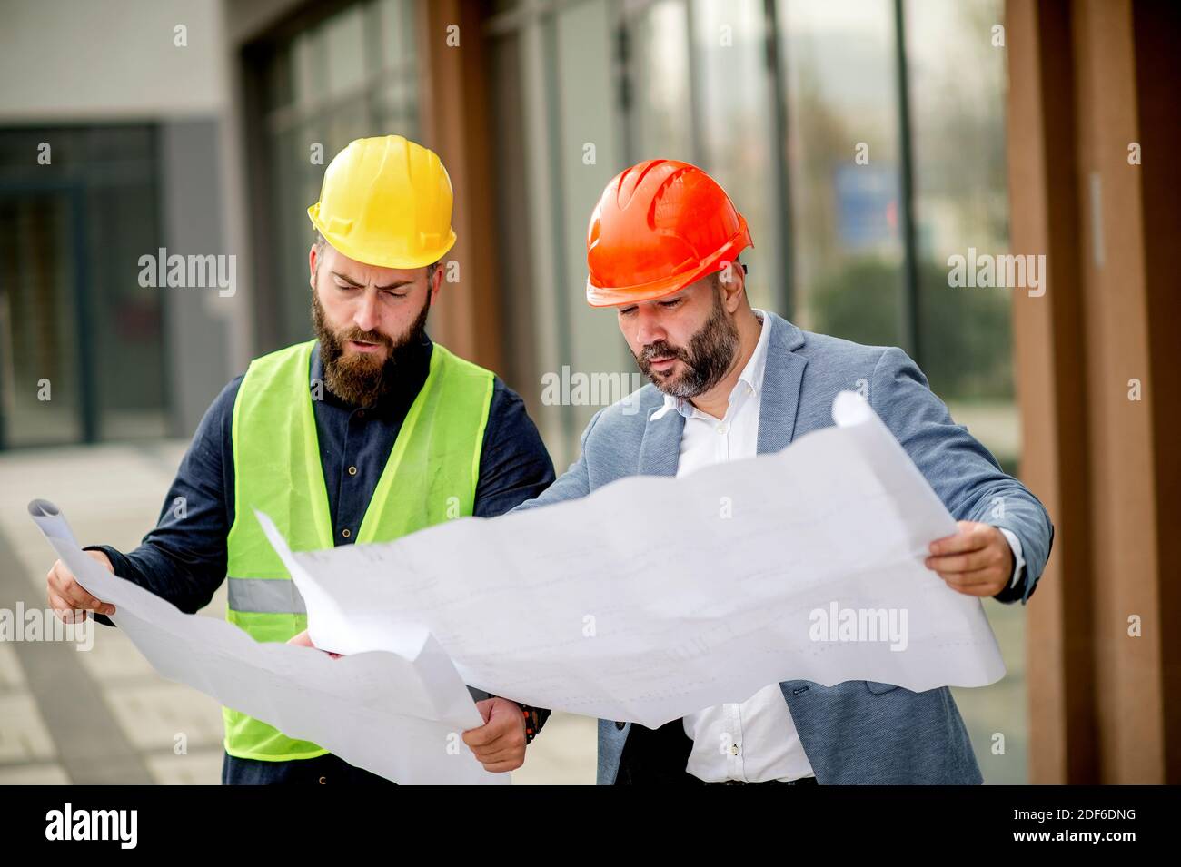 Two architects examining a blueprint and working on a building project. Stock Photo