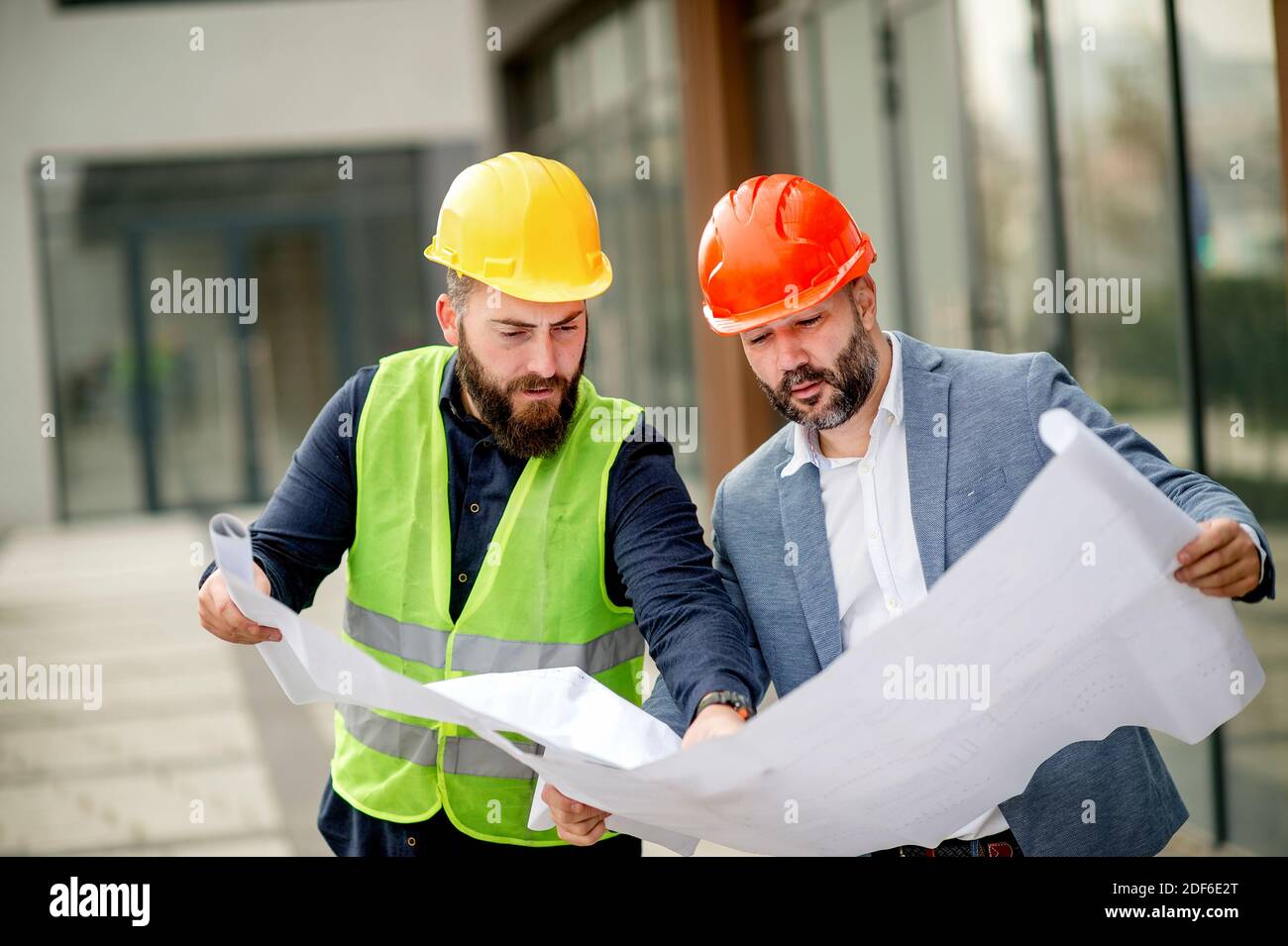 Two architects examining a blueprint and working on a building project. Stock Photo