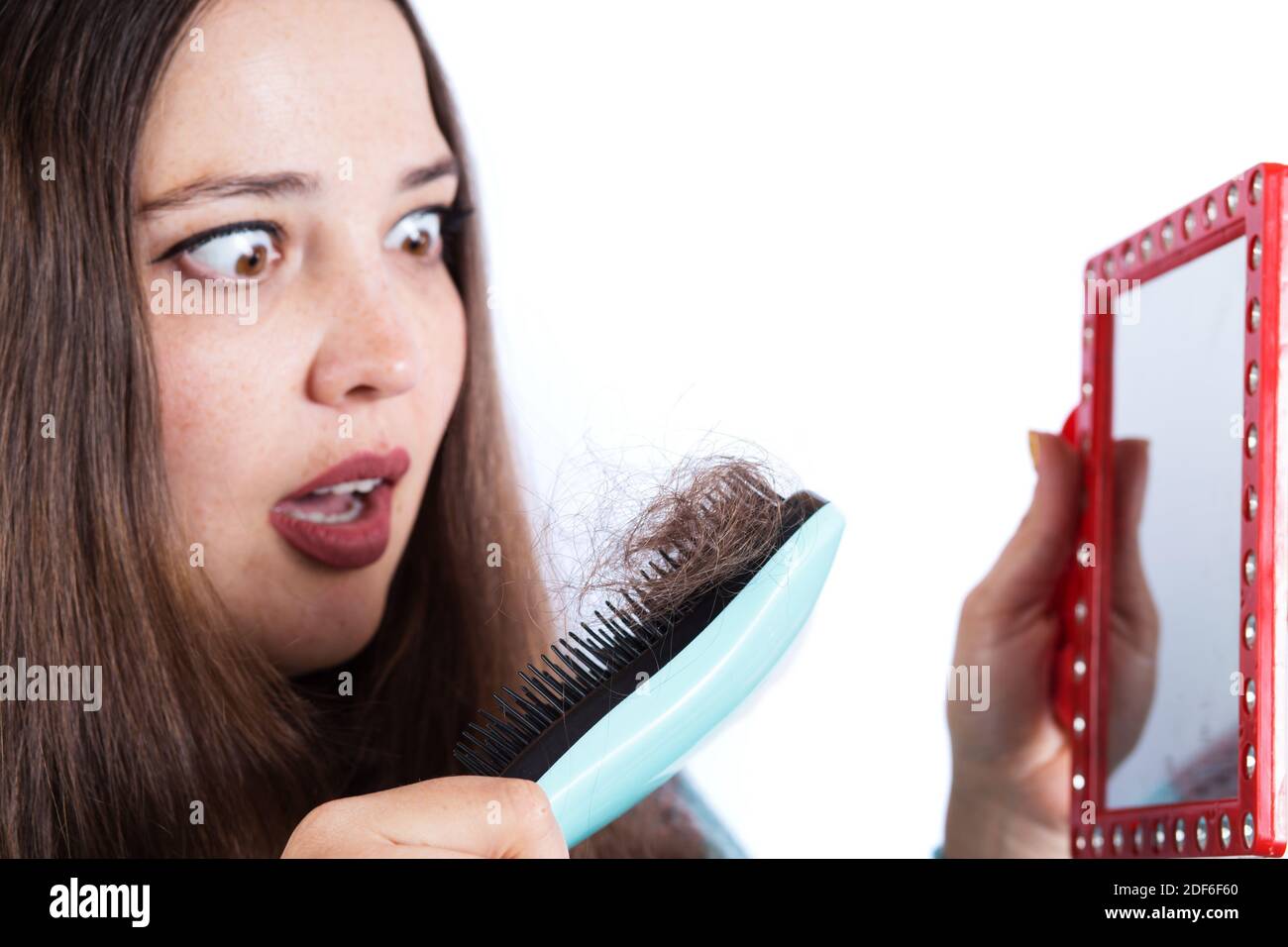 Young woman scared of loosing her hair, lost hair on a brush. Stock Photo