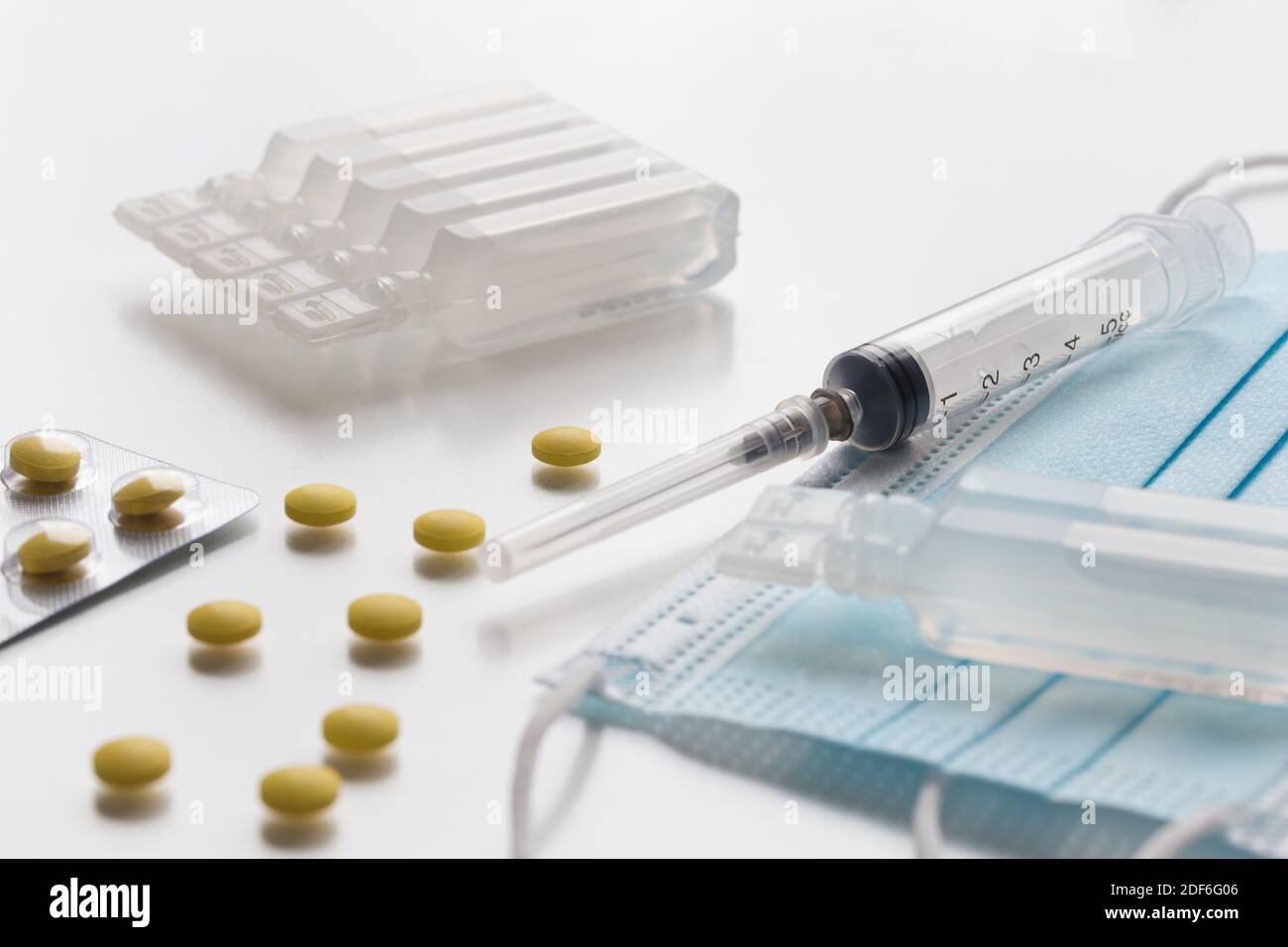 Medical face masks, yellow pills, ampullas and expendable syringe for vaccination. Coronavirus vaccination concept. COVID-19 outbreak - Wuhan, China. Stock Photo
