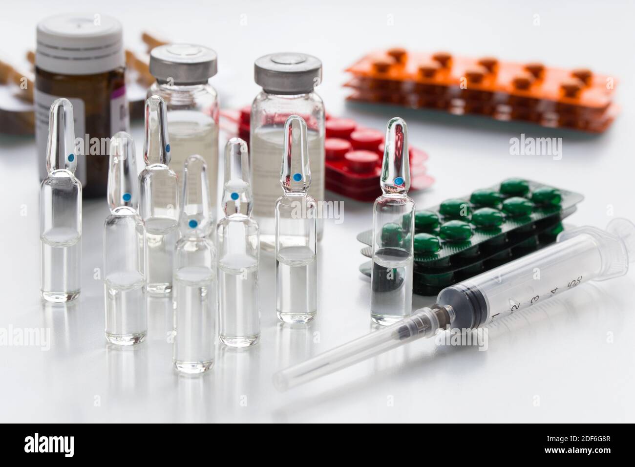 Medical bootles, colorful packaging with pills, ampullas and expendable syringe for vaccination. The concept of vaccination and treatment coronavirus. Stock Photo