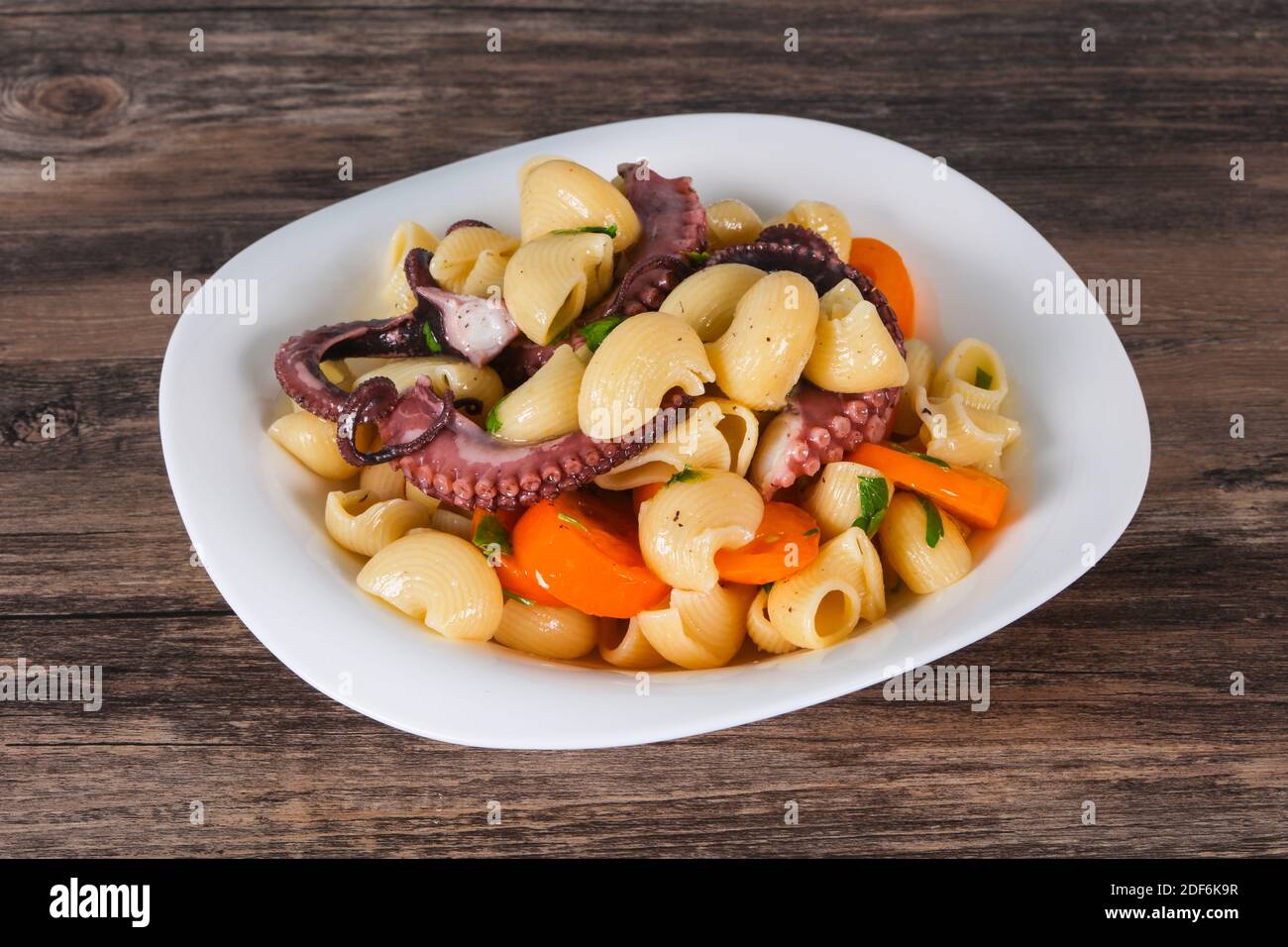 Pasta with octopus, parsley and yellow tomatoes Stock Photo - Alamy