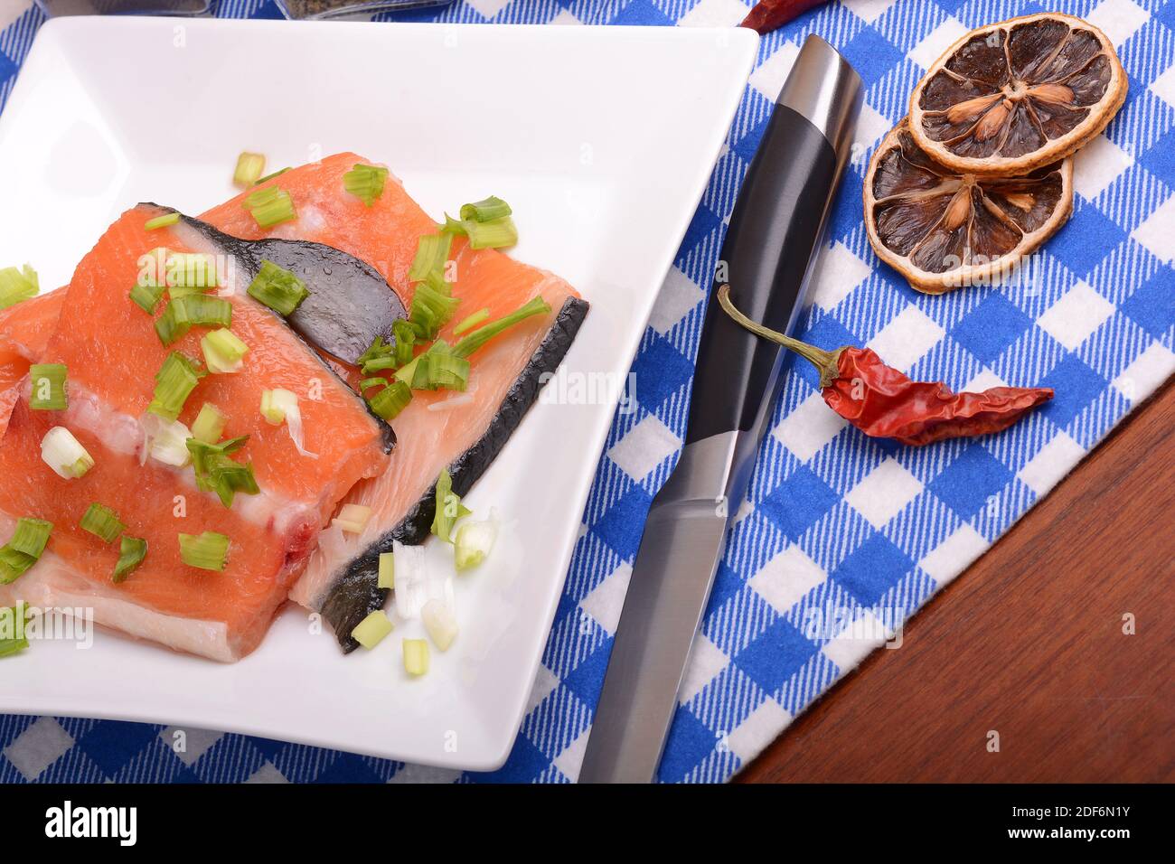 Food concept: red salmon fish, lemon and cabbage with red hot chilli pepper with greens. Healthy food cooking. Stock Photo