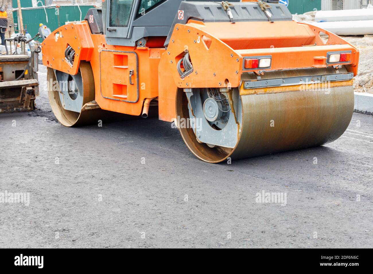 Construction of a new road. A large vibratory road roller paired with an  asphalt paver paving and compacting the hot asphalt on the new road Stock  Photo - Alamy