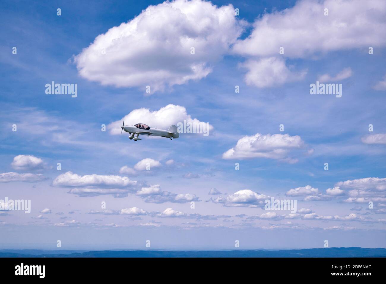 Small trainer aircraft flying in air, amidst the clouds. Horizontal view. Negative space, good for writing text. Suitable for background, cover photo. Stock Photo
