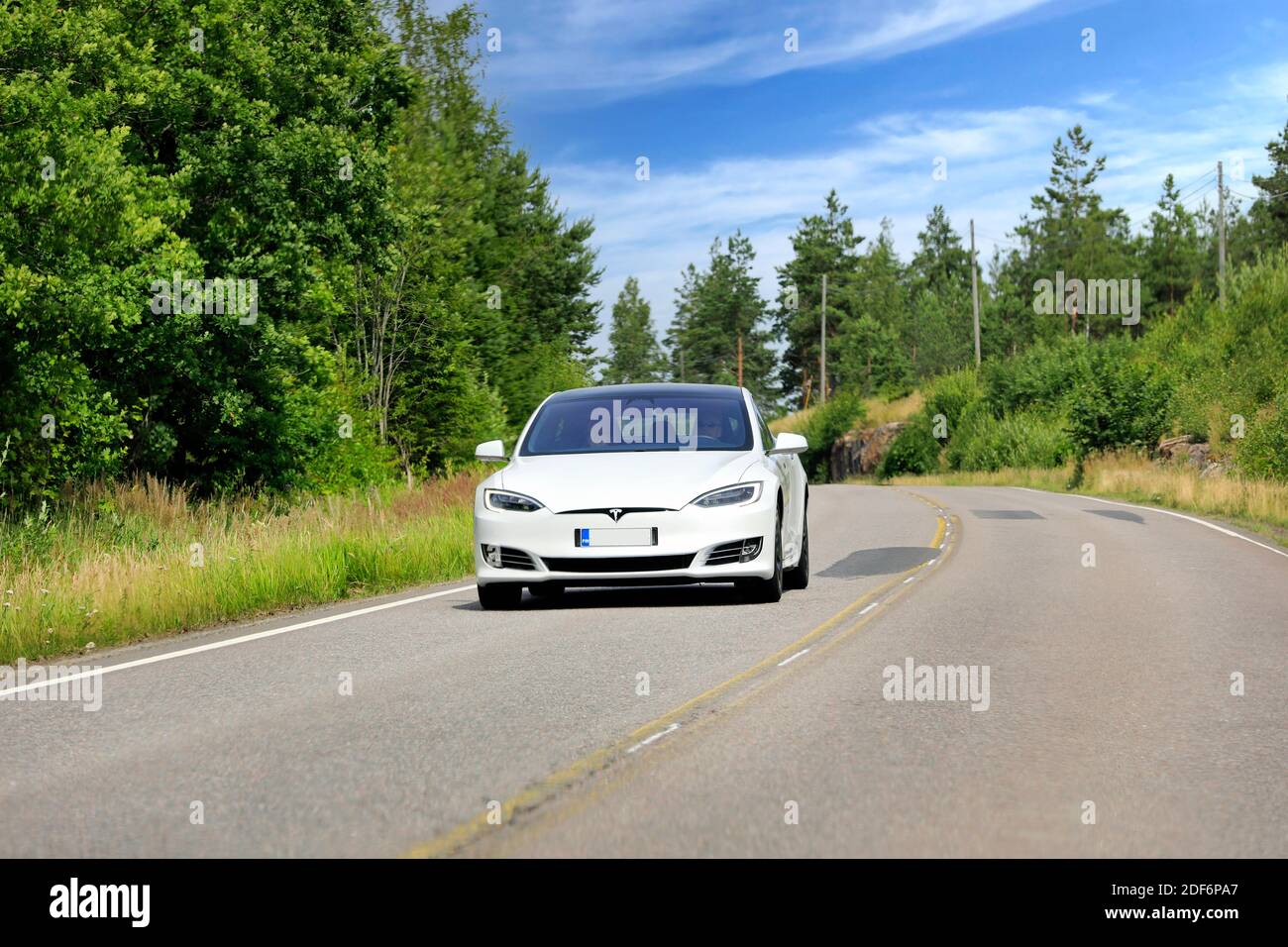 White Tesla Model S electric car driving at speed on rural highway through Finnish countryside in the summer. Salo, Finland. July 19, 2020. Stock Photo