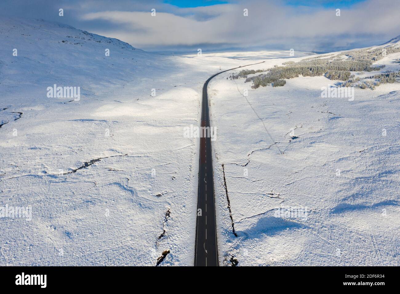 Glen Coe, Scotland, UK. 3 December 2020. A cold front has brought the first snowfall to the Scottish Highlands. Rannoch Moor and Glen Coe are covered in several inches of snow. Bright sunshine throughout the day created beautiful winter landscapes.  Pictured; Aerial view of A82 passing over snow covered Ranch Moor.  Iain Masterton/Alamy Live News Stock Photo