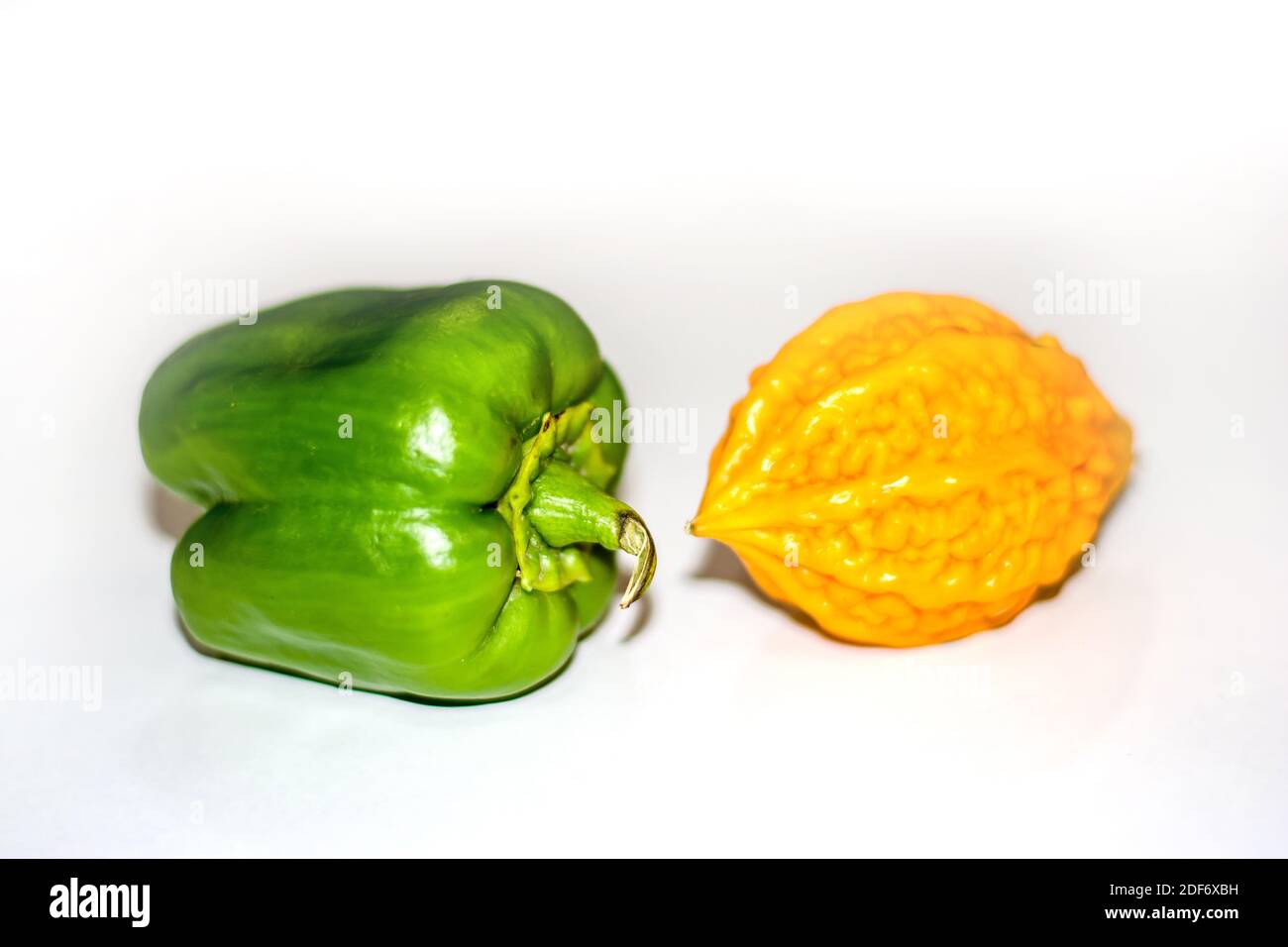 yellow bitter gourd between green capsicum with isolated background