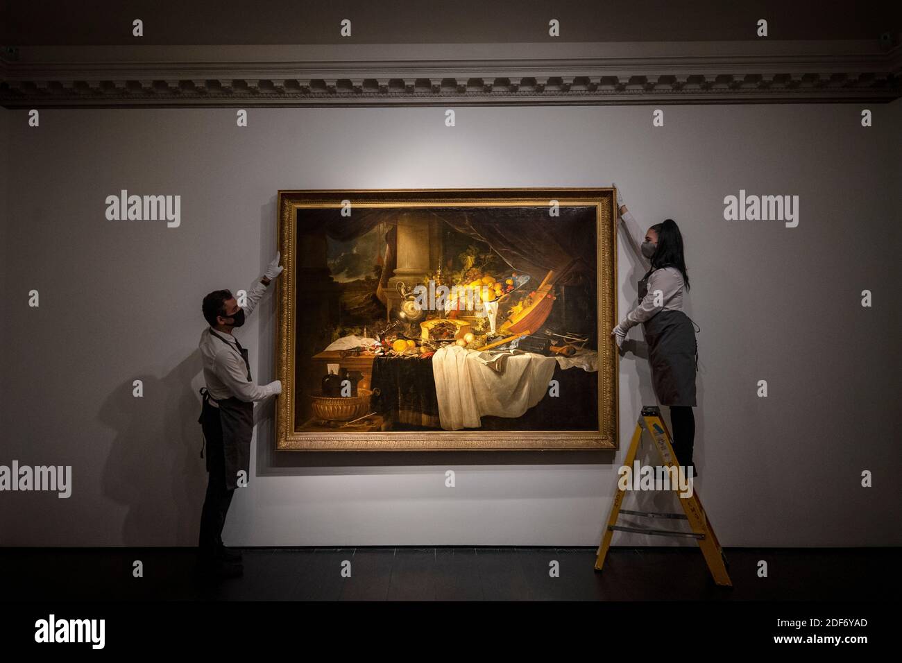 Gallery assistants adjust 'A banquet still life' by Jan Davidsz De Heem with an estimate of ??4-6 million, which is on show at Christie's saleroom in central London ahead of the auction house's forthcoming Classic Week sales. Stock Photo