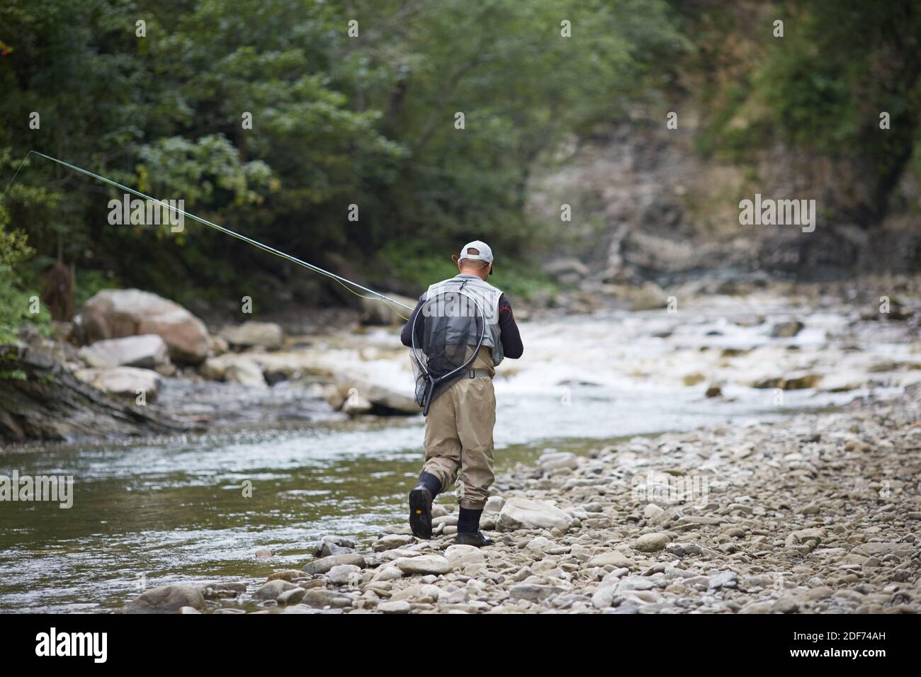 Back view of experienced fisherman dressed in waterproof clothing