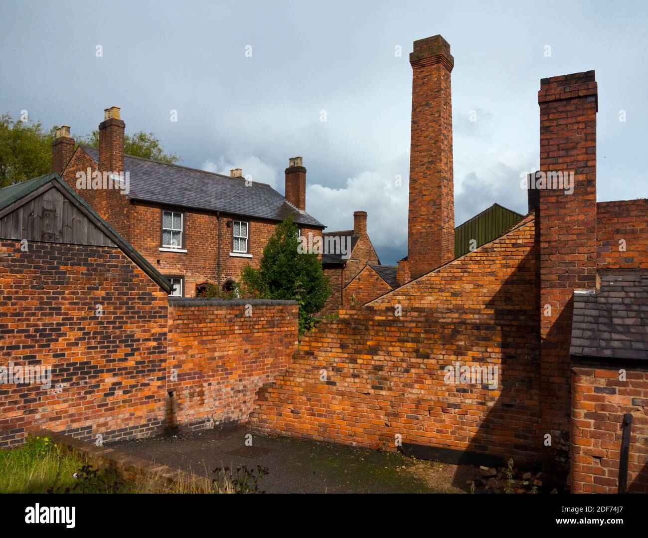 Red brick terraced house with yard and factory chimney on a street at the Black Country Living Museum in Dudley West Midlands England UK Stock Photo