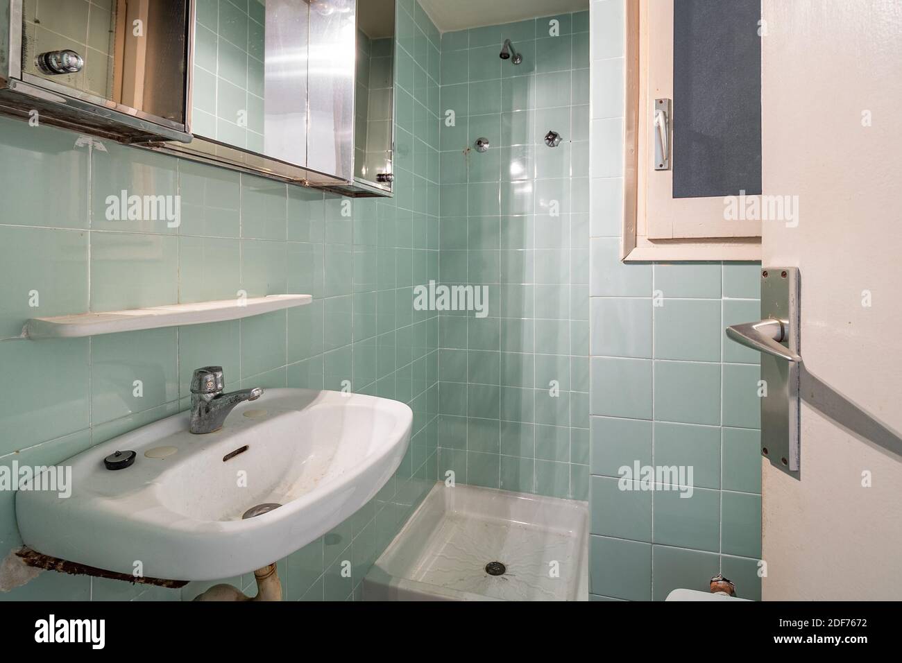Empty, old and dirty bathroom with blue tiles in an old house of