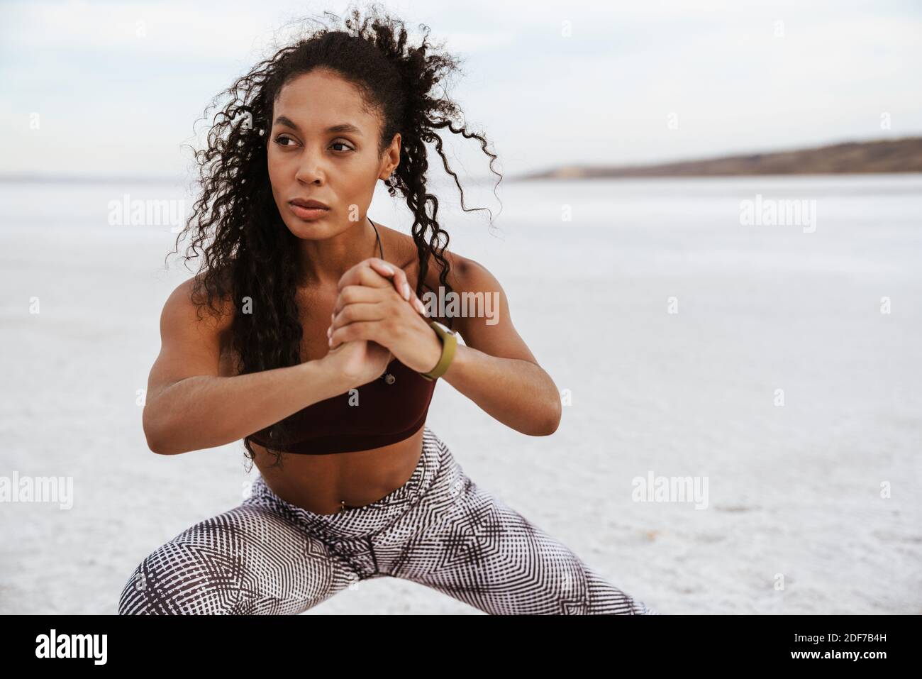 Confident young african woman doing stretching exercises at the salt ...