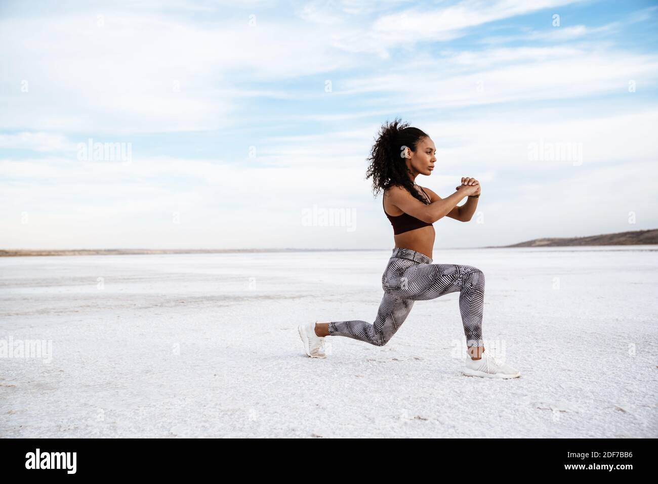 Confident young african woman doing stretching exercises at the salt ...