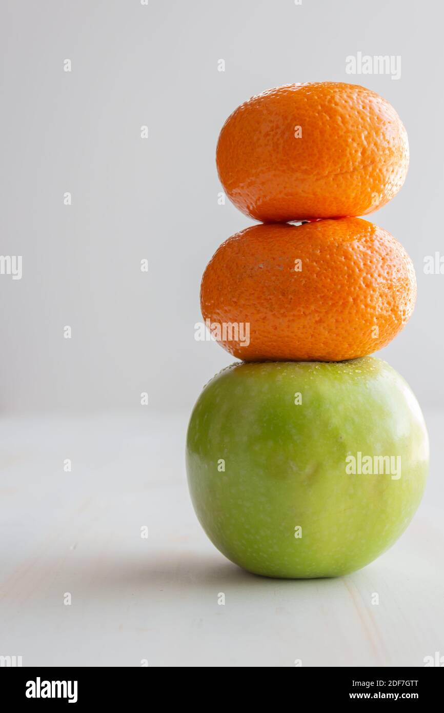 two oranges stacked on a green apple as a playful fruit snowman with copy space on white background Stock Photo