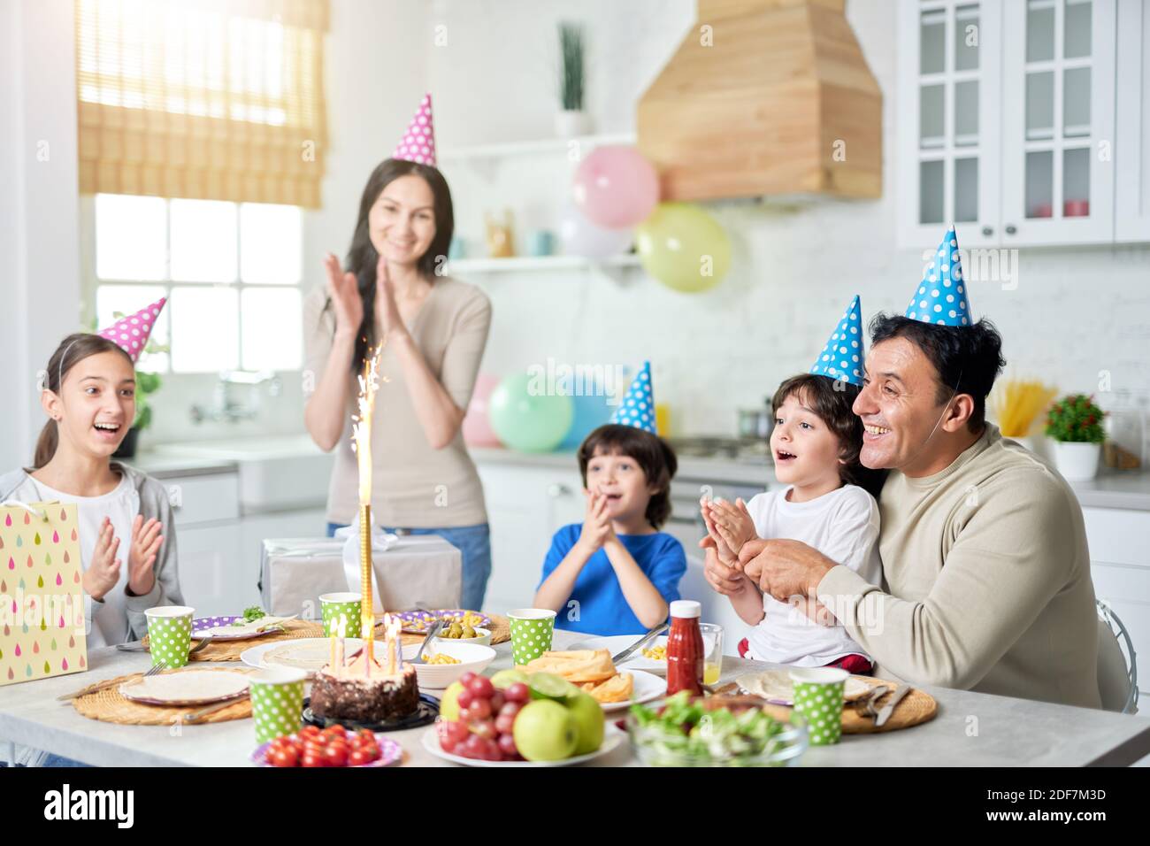 Joyful hispanic family with children looking happy, clapping while celebrating birthday together at home. Parenthood, celebration concept. Selective focus Stock Photo