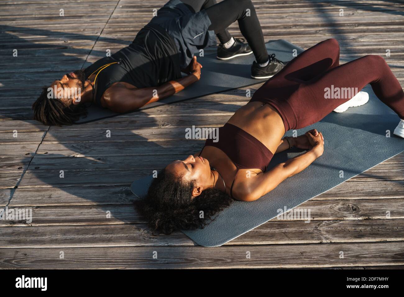 Attractive young african couple doing stretching exercises outdoors ...