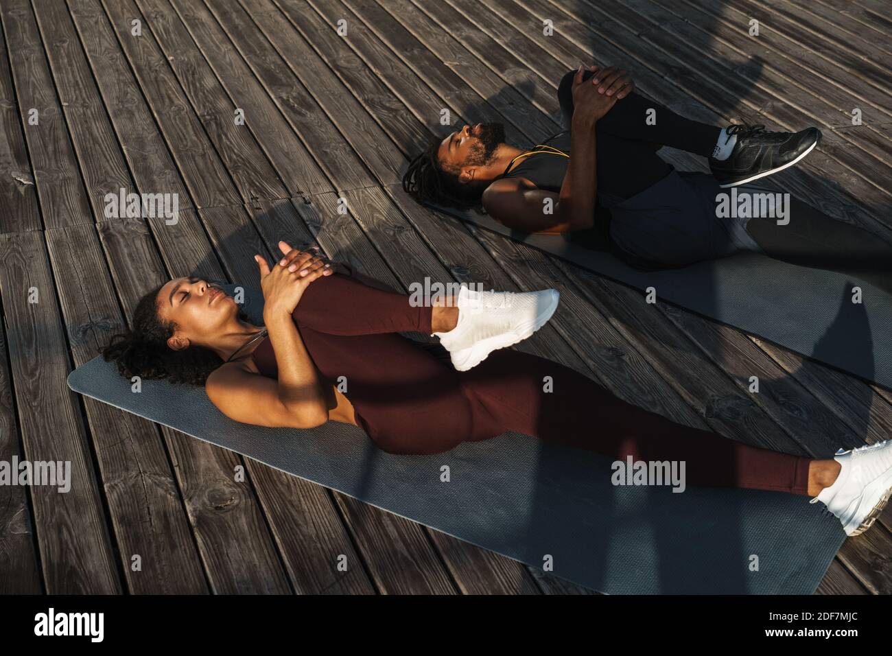 Attractive young african couple doing stretching exercises outdoors ...