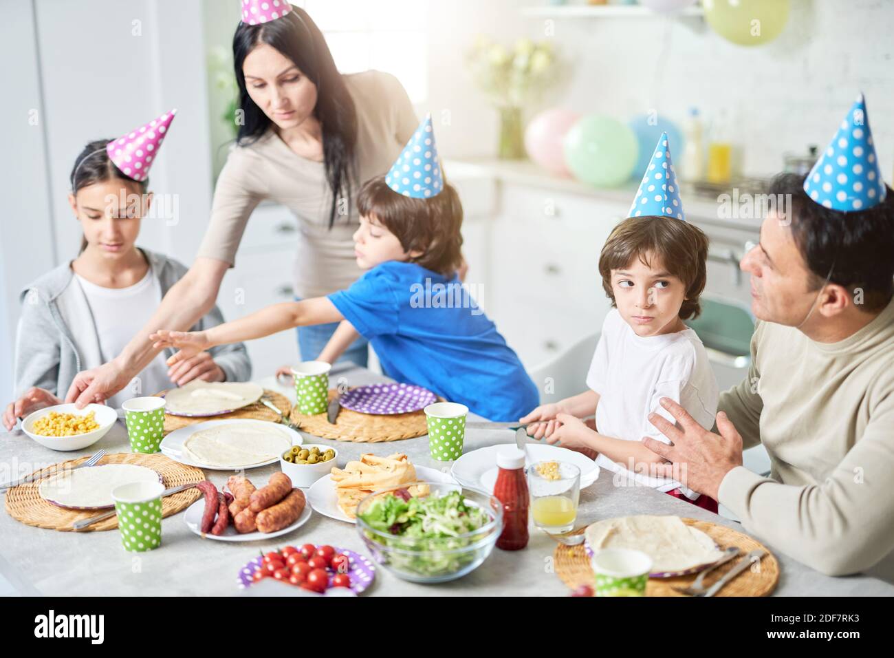 Loving dad talking to his little son. Hispanic family having dinner while celebrating birthday together at home. Parenthood, celebration concept. Selective focus Stock Photo