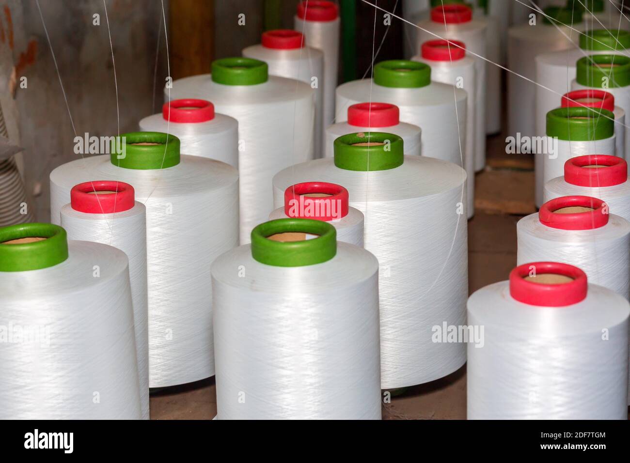Red-green spools of white yarn in a garment factory. Weaving loom in a textile factory. Stock Photo