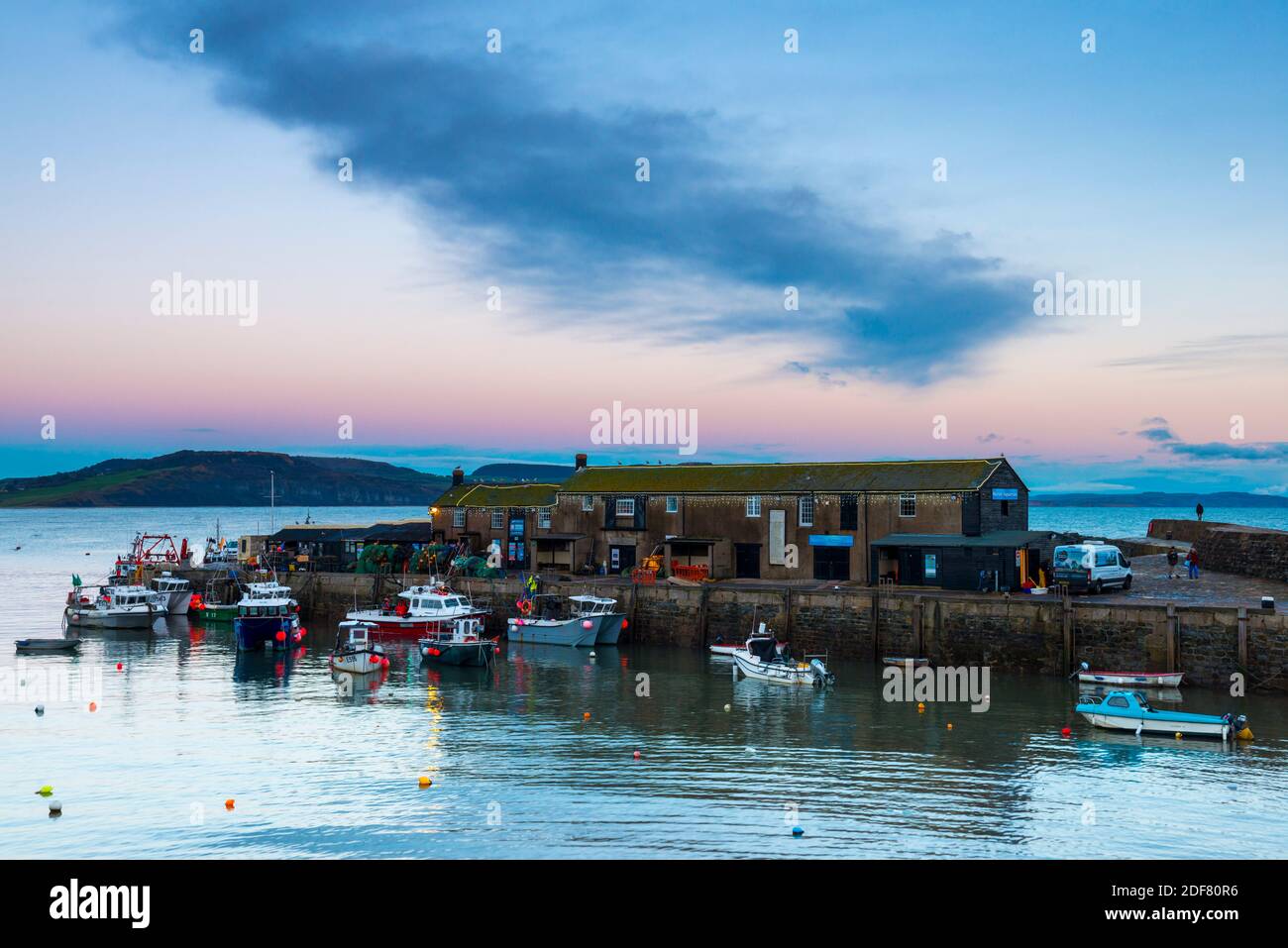 Lyme Regis, Dorset, UK.  3rd December 2020.  UK Weather.  A pink glow in the sky above the Cobb harbour at Lyme Regis in Dorset shortly after sunset.  Picture Credit: Graham Hunt/Alamy Live News Stock Photo
