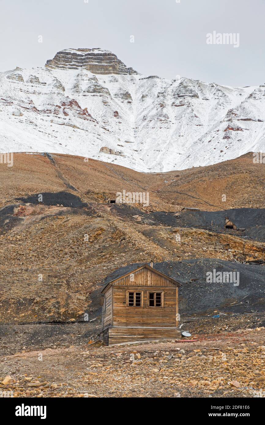 Old wooden hut and adits / coal mine entrances on mountain slope at Pyramiden, abandoned Soviet coal mining settlement on Svalbard / Spitsbergen Stock Photo