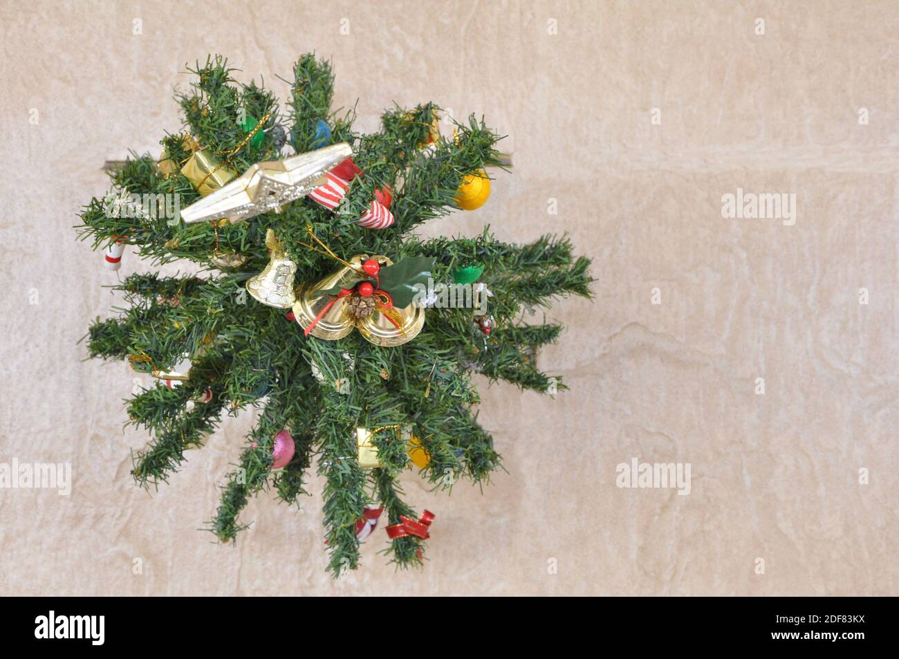 Christmas tree assembled with Santa Claus accessories in top view on ceramic floor background Stock Photo
