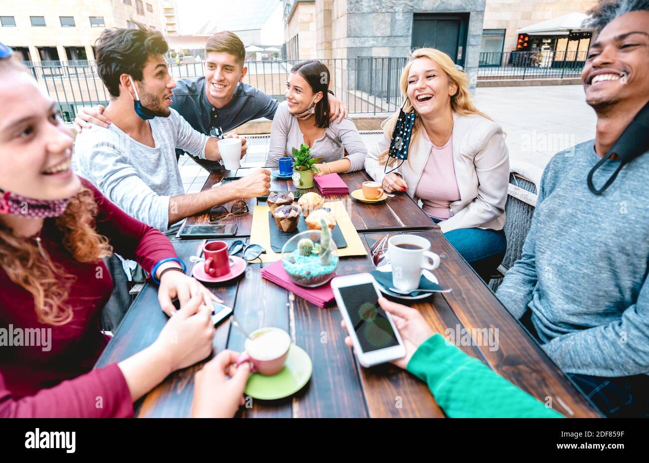 Friends having fun drinking cappuccino at coffeehouse - Young people talking together at restaurant cafeteria - New normal lifestyle concept Stock Photo