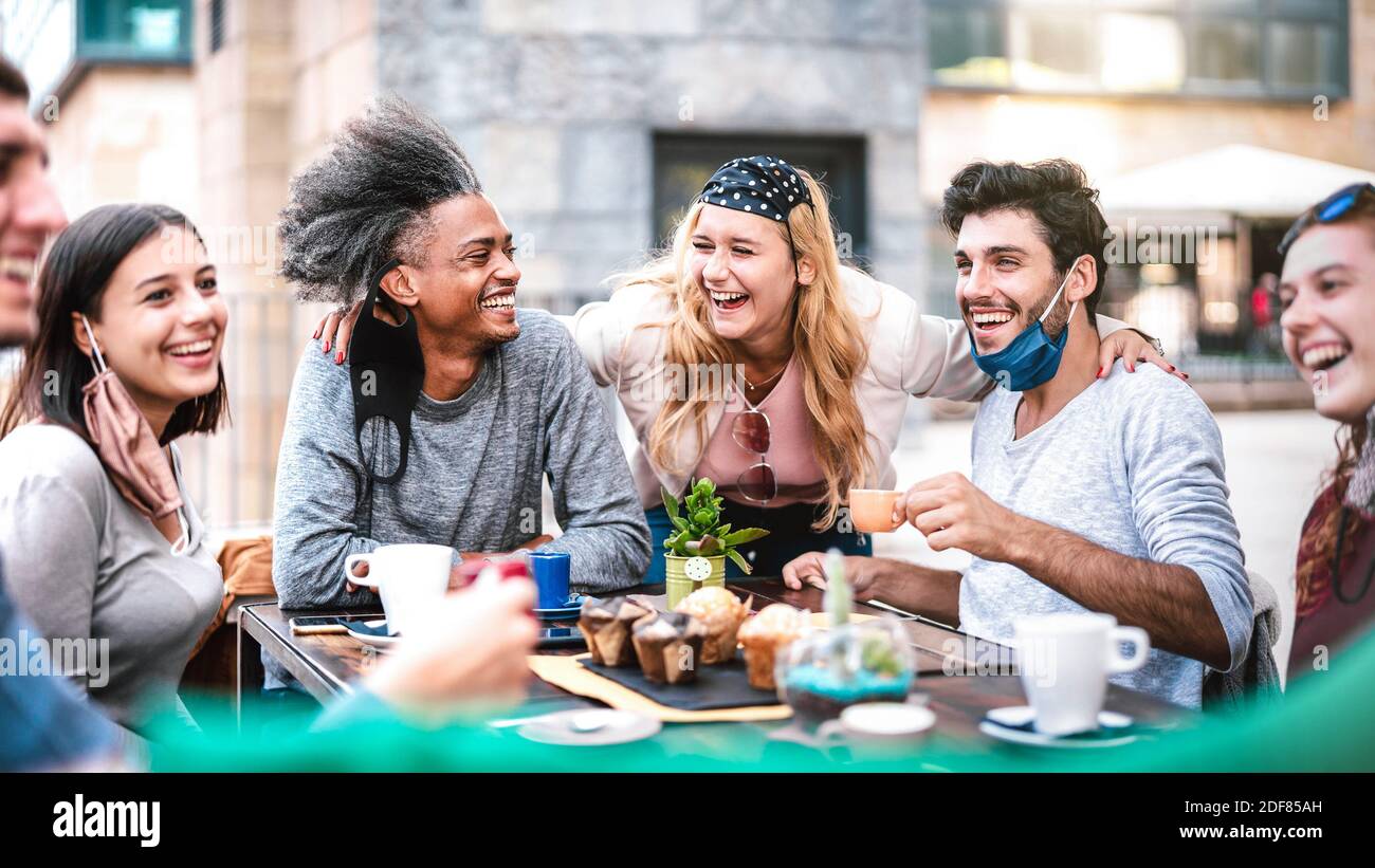 Multiracial people having fun drinking at outside coffeehouse - Young friends talking together at restaurant - New normal lifestyle concept Stock Photo
