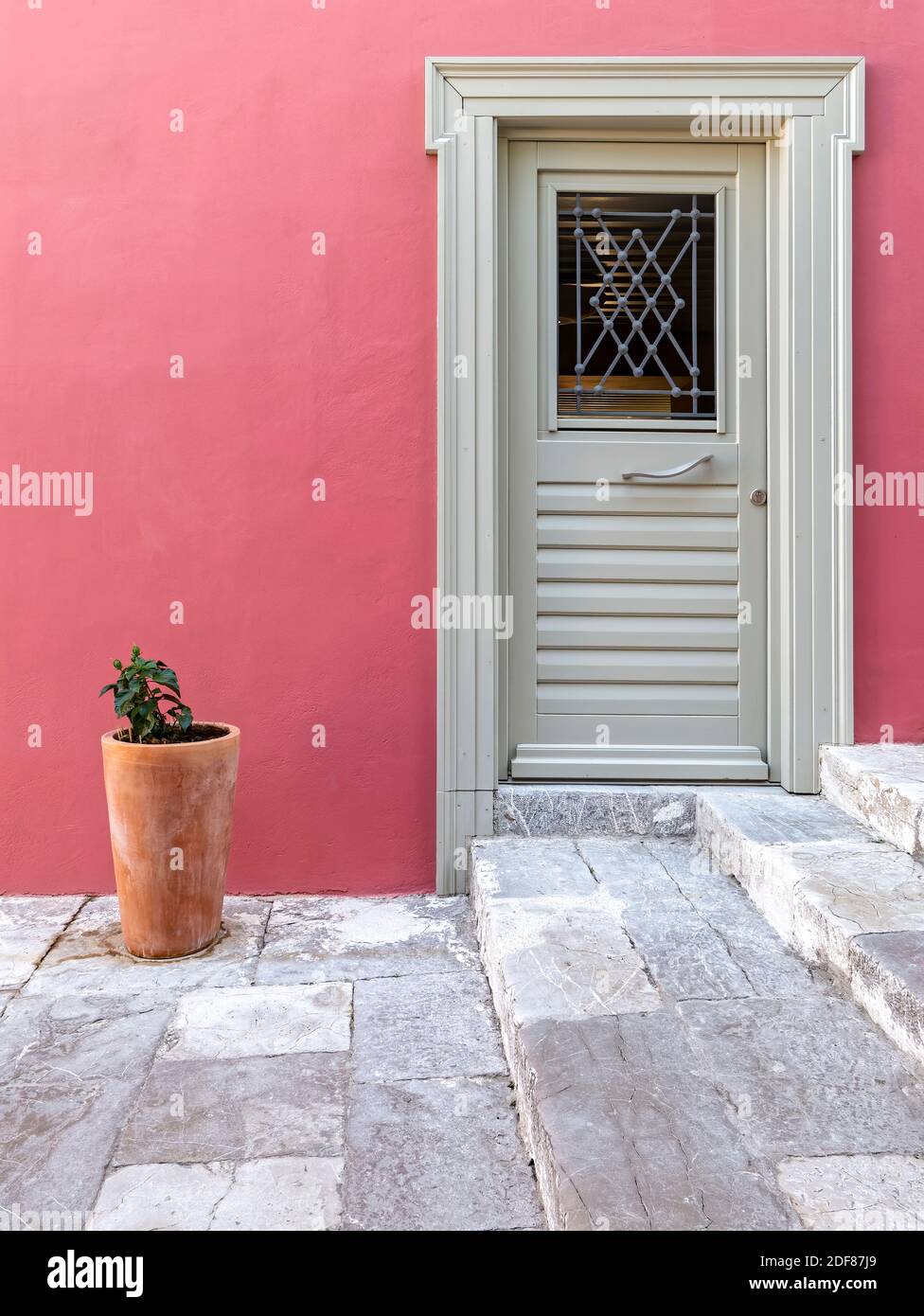 Saumon Gray Home I. A vivid colored house, dark pink wall with pale gray entrance door by the cobblestone sidewalk. Stock Photo
