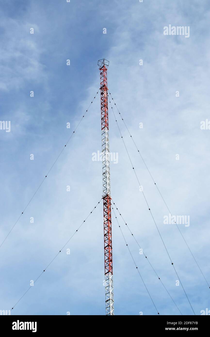 Tall red and white radio communication mast with supporting guy-wires. Stock Photo