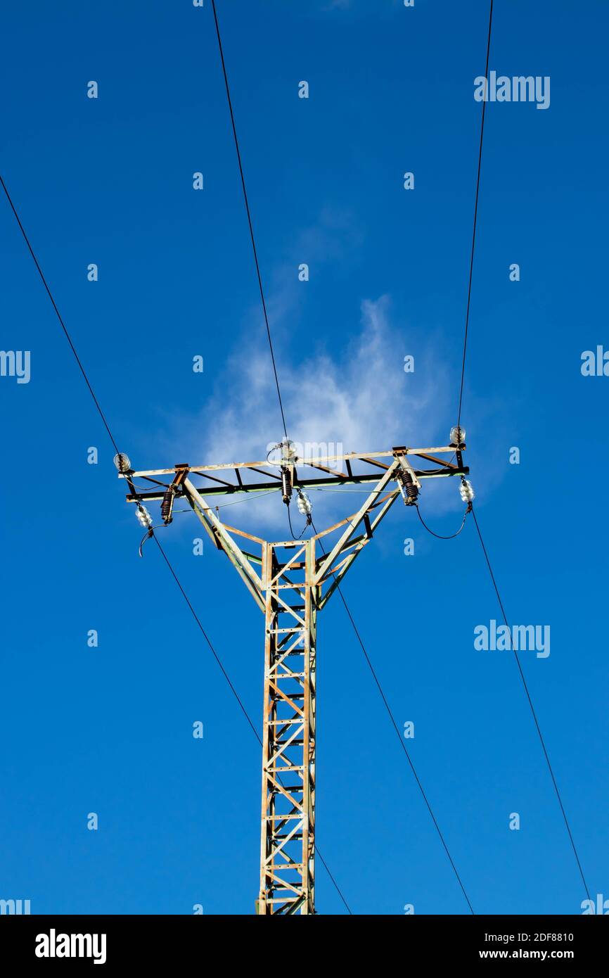 Power line pilon. Energy transmission and distribution. High voltage overhead electric line. Clear blue sky. Stock Photo