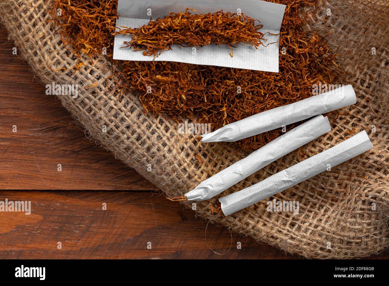 https://c8.alamy.com/comp/2DF88GB/cigarette-paper-and-pile-of-tobacco-on-wooden-table-2DF88GB.jpg