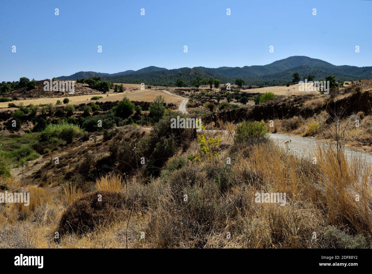 Small gravel road twisting through rugged dry countryside of rural southern Cyprus Stock Photo