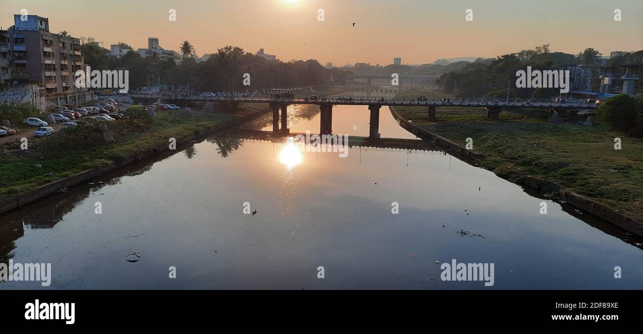 A sunset reflection capture on mutha river from shivaji Bridge pune. Polluted mutha river pune. Stock Photo