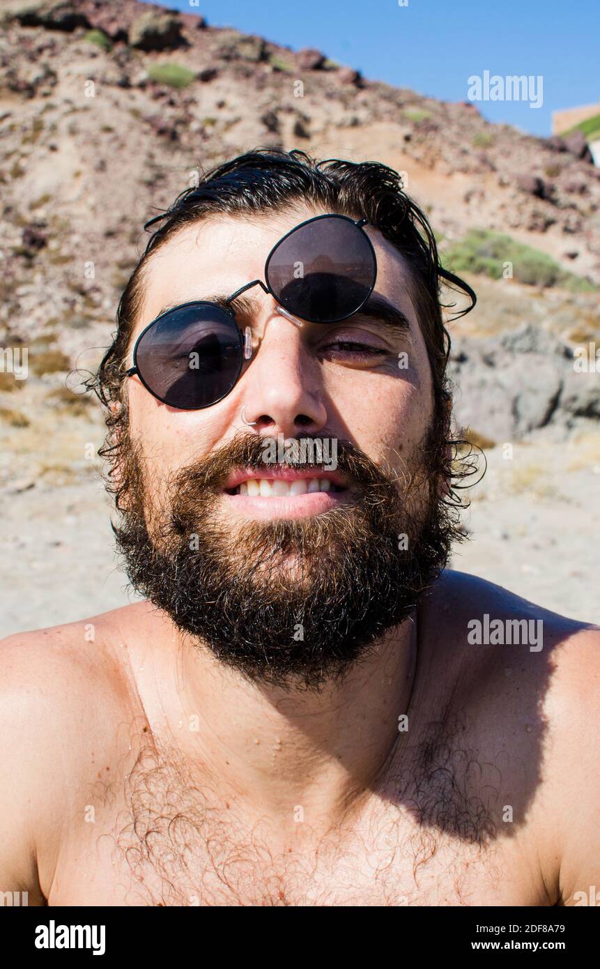 young man with wet hair after a bath on the beach wears sunglasses in casual style Stock Photo