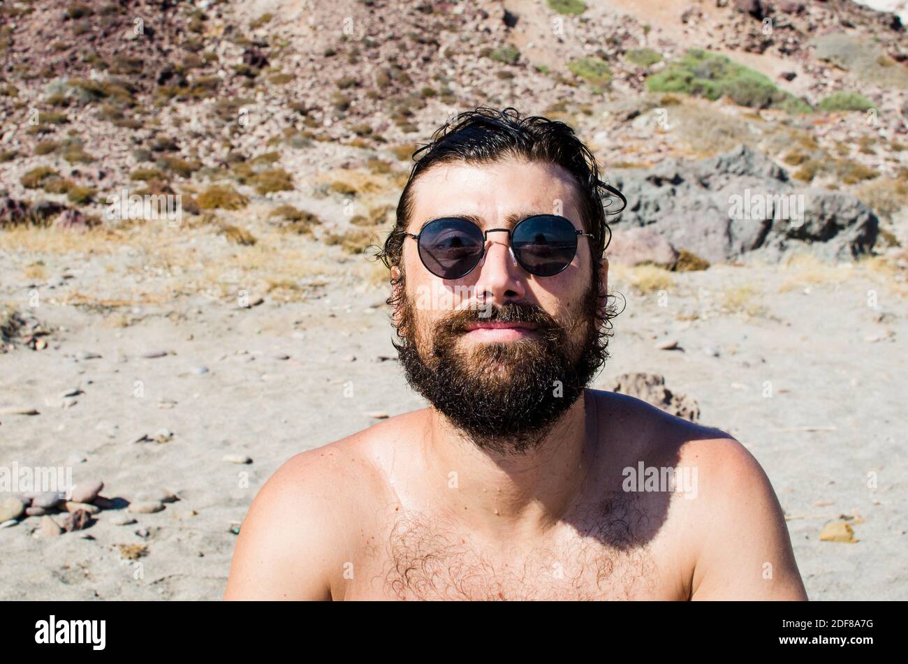 young man with wet hair after a bath on the beach wears sunglasses in casual style Stock Photo