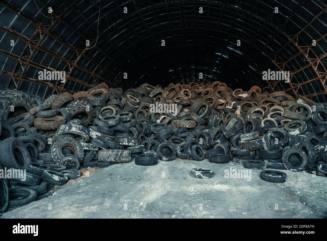 Large pile of old used car and truck tires in abandoned hangar. Stock Photo