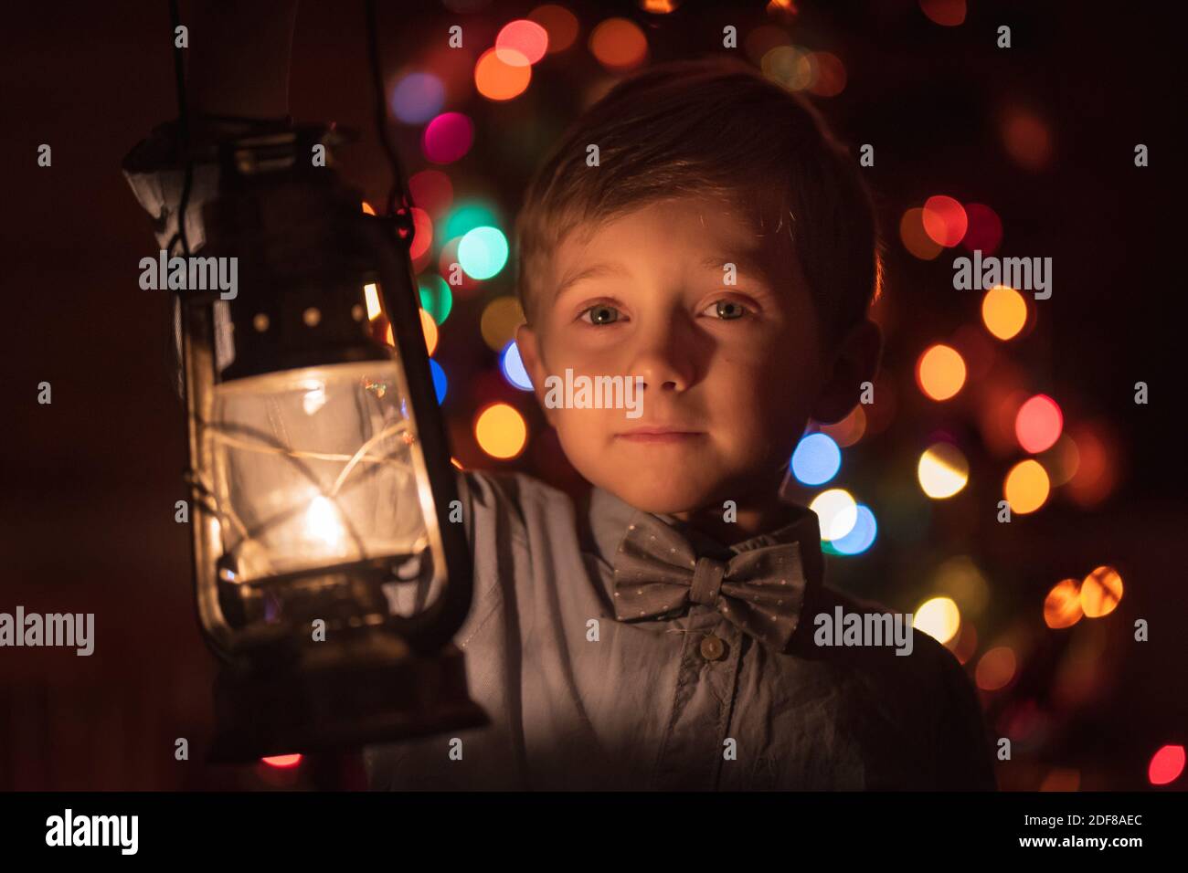 Portrait of 6 years old with oil lamp and Christmas tree in the background Stock Photo