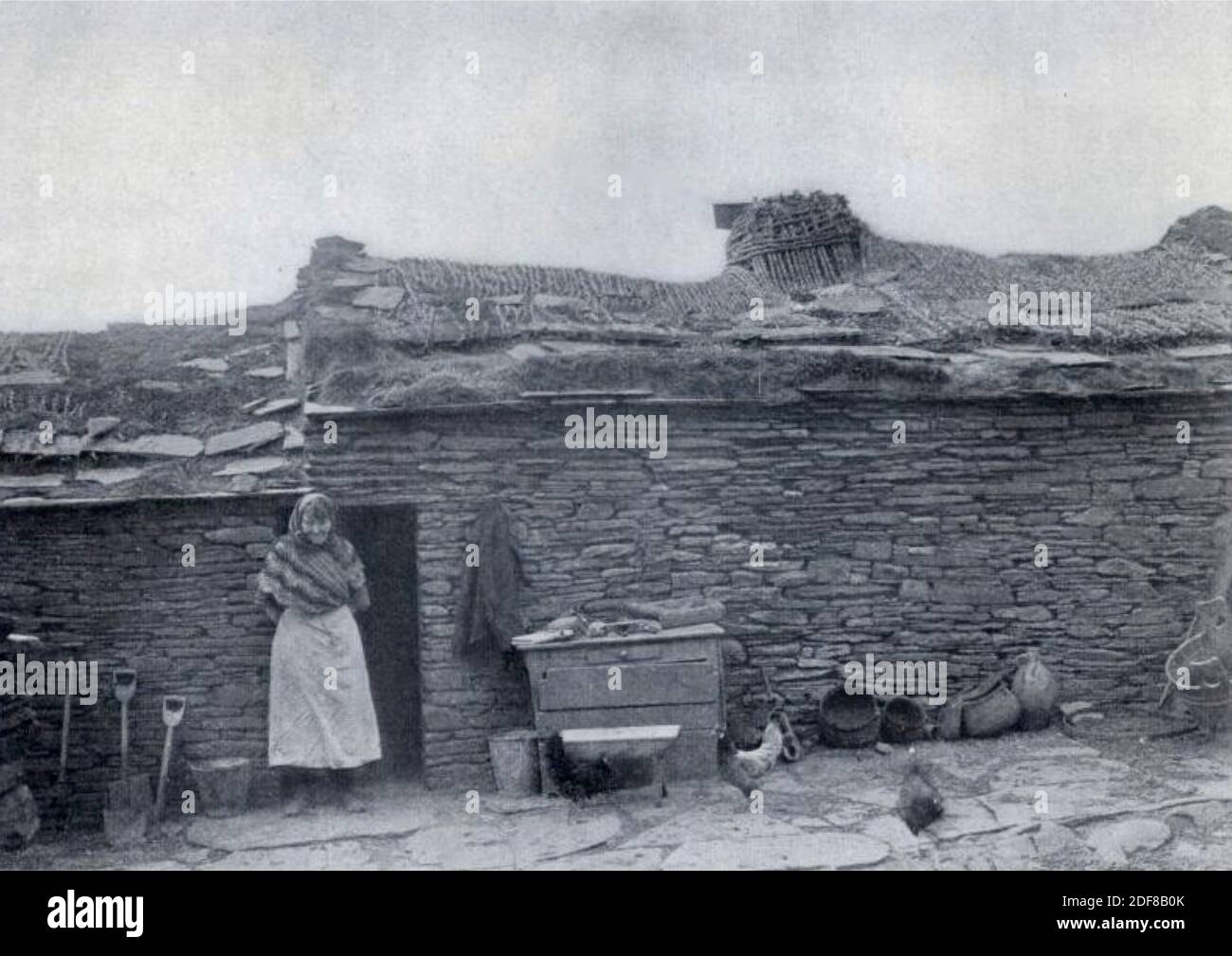 Vintage photograph of a woman crofter standing outside of her croft house in Scotland. Stock Photo