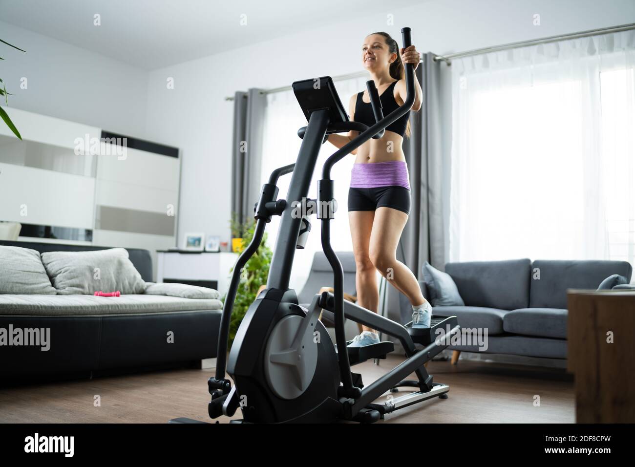 Woman Training On Elliptical Trainer At Home Stock Photo