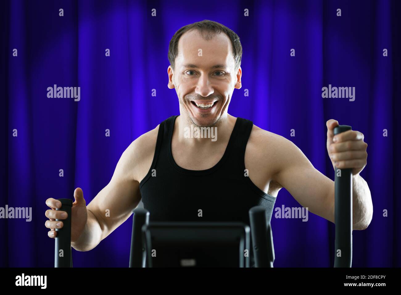 Man Training On Elliptical Trainer At Home Stock Photo